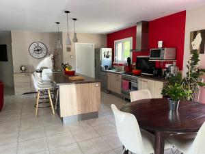 a kitchen with red walls and a table and chairs at Villa en pleine nature avec piscine in Sablières