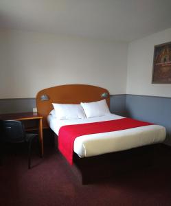 a hotel room with a bed with a red blanket at Quick Palace Le Mans in Saint-Saturnin
