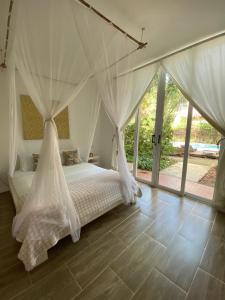 una camera da letto con un letto con tende bianche di Kawabonga a Palomino
