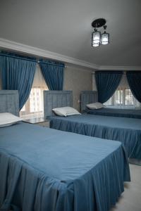 2 letti in una camera con tende blu di Welldone HOTEL a Samarkand