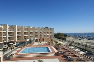 a hotel with a swimming pool in front of a beach at Real Marina Hotel & Spa in Olhão