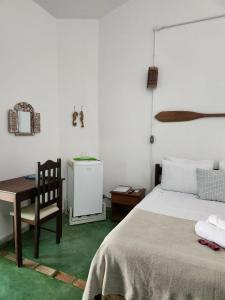 a bedroom with a bed and a table and a chair at Pousada São Francisco in Cumuruxatiba
