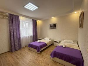 two beds in a room with purple sheets at Гостиница ,,Меркурий и К,, in Astana +23 photos