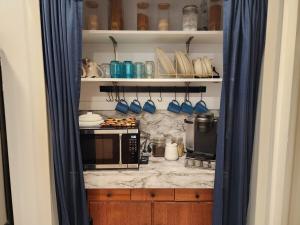 a kitchen with a microwave and blue curtains at 3BR Oasis with Pool in Cocoa in Cocoa