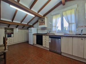 a large kitchen with white appliances and a large window at Casa de campo en Hontoria, Selnatur in Cardoso