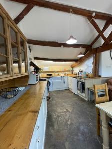 a large kitchen with white cabinets and wooden counters at Worcester semi rural bungalow with off road parking in Upton Snodsbury