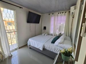 a bedroom with a bed and a tv and a window at Casa Plenitud Lux in Cartagena de Indias