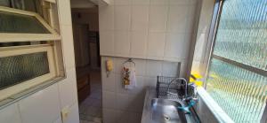 a bathroom with a sink and a window at ESD01- Ar Condicionado 5min a pé da Praia da Enseada, Apartamento in Guarujá