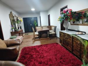 a living room with a table and a red rug at Pousada Canto dos pássaros in Cianorte