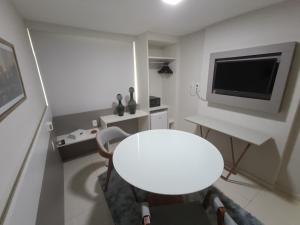 a white room with a white table and a tv at Trip Hotel Ubá - perto da Faculdade OZANAM COELHO e Eventos HORTO FLORESTAL in Ubá