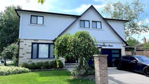 a white house with a car parked in front of it at Luxury Modern Retreat, Sauna, Theatre, Pool Table in Mississauga