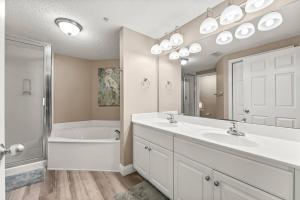 a bathroom with two sinks and a tub and a shower at Majestic Beach Resort 1404 in Panama City Beach +24 photos