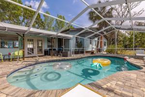 a swimming pool in a house with an umbrella at Basque Bungalow with pool, minutes to beaches in Bradenton
