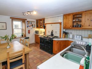 a kitchen with wooden cabinets and a sink and a table at Footdee Cottage in Aberdeen