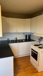a kitchen with white cabinets and a stove and a sink at Apartment Vestpollen in Vestpollen