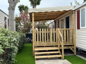 una terraza de madera con toldo en el lateral de una casa en MOBIL HOME l'ETOURNEAU, en Valras-Plage