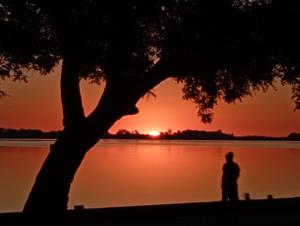 a person standing in front of a lake at sunset at Espectacular casa centro laguna para parejas in Chascomús