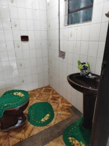 a bathroom with a toilet and a sink with green mats at Pousada Canto dos pássaros in Cianorte +7 photos