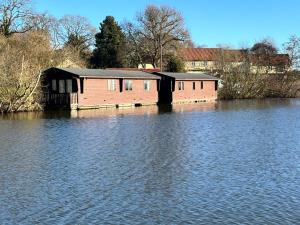 a house sitting in the middle of a body of water at Bure River Lodge Houseboat in Stalham