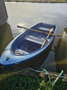 a blue boat sitting in the water with two paddles at Bure River Lodge Houseboat in Stalham +13 photos
