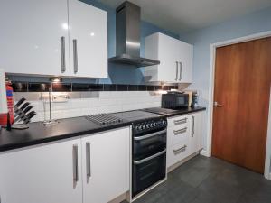 una cucina con mobili bianchi e un forno a piano cottura di Molly's Cottage a Grasmere Altre 15 foto