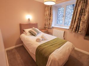 una piccola camera da letto con un letto con asciugamani sopra di Molly's Cottage a Grasmere