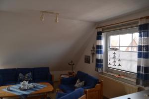 a living room with blue couches and a table and a window at Haus Schimmelreiter in Greetsiel