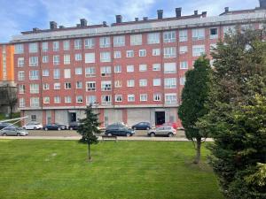 a large red building with cars parked in a parking lot at Apartamento San Lázaro. in Oviedo