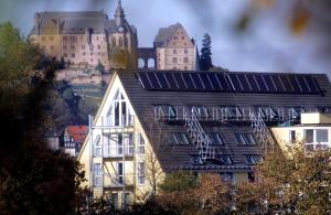 a building with solar panels on it in front of a castle at Hotel im Kornspeicher in Marburg an der Lahn