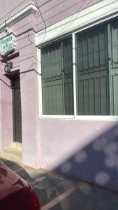 a pink building with large windows on a street at Posada don rulo in Mazatlán