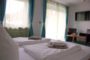 two beds in a hotel room with blue curtains at Hotel Buchrain in Göppingen