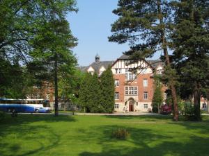 a large brick building with trees in front of it at Hotel Willa Park in Żagań