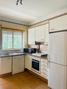 a kitchen with white cabinets and a white refrigerator at Praia D'El Rey Pool & Golf House in Amoreira