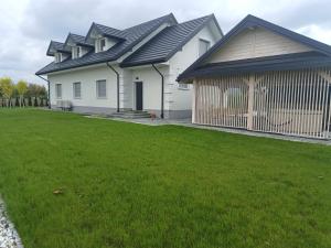 a large white house with a green yard at Apartamenty Noclegowe U Bartosza in Odrzechowa