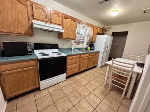a kitchen with wooden cabinets and a white stove top oven at River Hideout: One Bedroom Duplex Cottage ON THE RIVER!! in Ruidoso