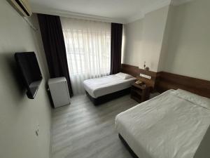 a hotel room with two beds and a television at Altinnal Hotel in Kocaeli
