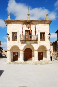 un gran edificio de piedra con balcón y 2 banderas en Casa Rural Margarita'S en Sotillo de la Ribera