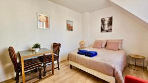 a bedroom with a bed and a table and a desk at Studio Pavot - 15min Paris RER E, cosy in Noisy-le-Sec