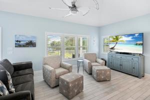 sala de estar con sofá, sillas y TV de pantalla plana en 152 Steps to the Beach! Heated Pool - Steps Away - Roelens, en Fort Myers Beach
