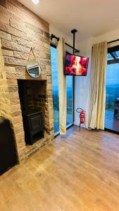 Una sala de estar con chimenea de piedra y televisor de pantalla plana. en Ninho da Águia - Cabana A, en Urubici