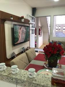 ein Wohnzimmer mit einem TV und einem Tisch mit Blumen in der Unterkunft Vivendas do Rio 1 in Ananindeua