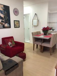 ein Wohnzimmer mit einem Tisch und einem roten Stuhl in der Unterkunft Vivendas do Rio 1 in Ananindeua