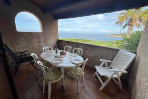 a table and chairs on a balcony with the ocean at Appartement en bord de mer Marine de Sant-Ambrogio in Lumio
