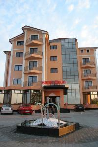 ein Gebäude mit einem Brunnen vor einem Gebäude in der Unterkunft Hotel Coral in Satu Mare