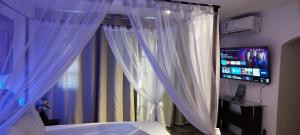 a bedroom with a bed with white curtains and a television at Arraial do Cabo - Suite master in Arraial do Cabo