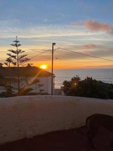 una puesta de sol sobre el océano con un edificio y un árbol en Maçãs Home-Sky sea view at The Beach, en Colares