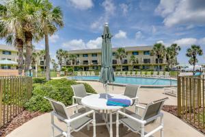St Augustine Resort Condo - Walk to Crescent Beach في سانت أوغيستين: طاولة مع مظلة وكراسي بجوار حمام سباحة