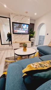a living room with a blue couch and a tv at Cosy Home near Central London in Grays Thurrock