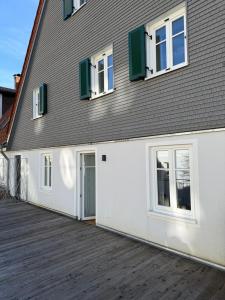 a white building with green windows and a wooden deck at Direkt am Marktplatz - Freudenstadt und Schwarzwald erleben in Freudenstadt
