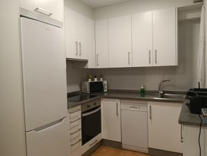 a white kitchen with white cabinets and a microwave at PISO BENITO in Ourense